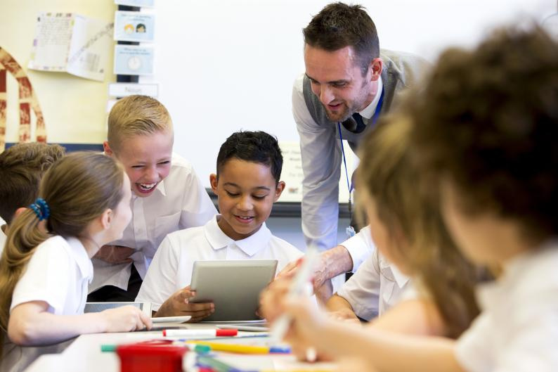 School children sitting around a table with their teacher