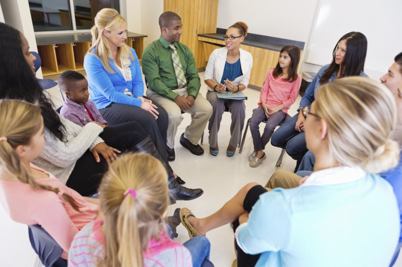 Group of adults and young people sitting around in a circle