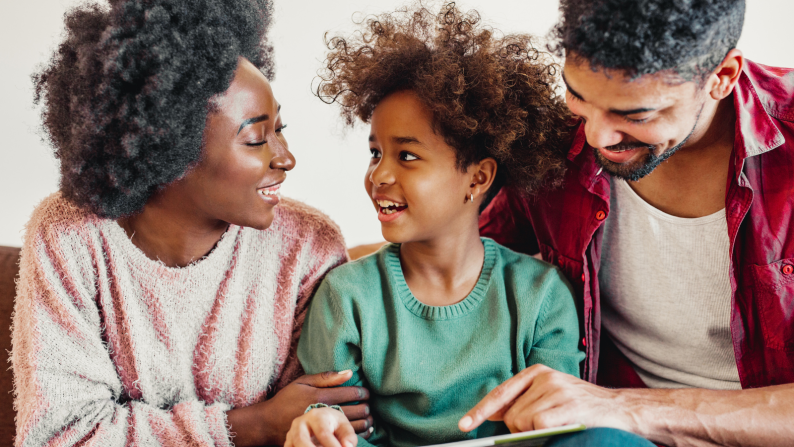 Two parents speaking to their smiling child