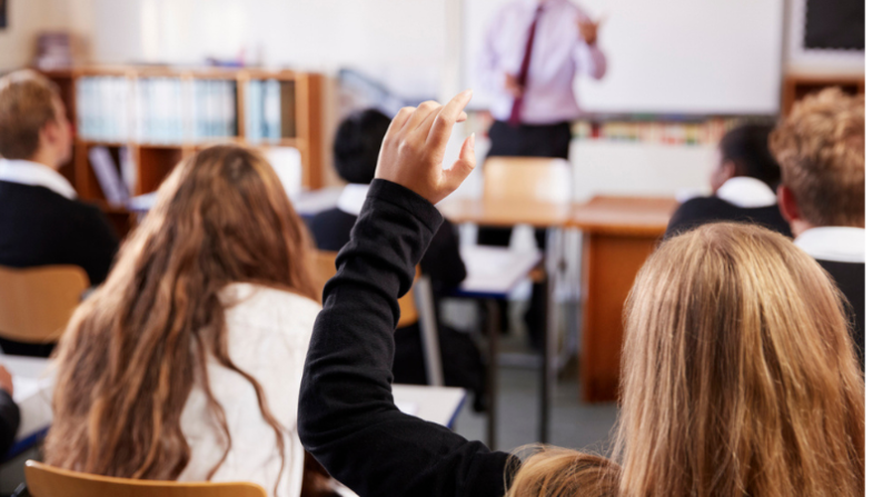 Young persons hand raised in class
