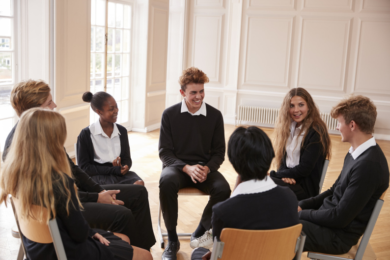 Children sitting around in a circle speaking.
