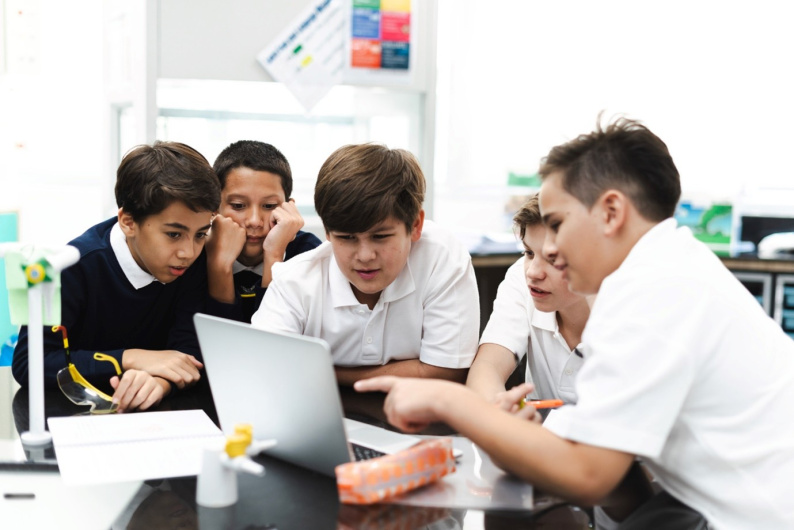 Student discussion in front of a laptop.